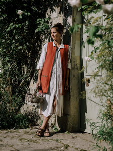woman leaning against door in red tweed gilet with basket