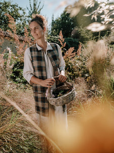 woman in blue check tweed gilet  in garden with basket